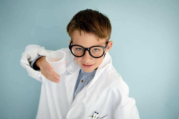 istock young cool boy ,with big massive black glasses is dressed up as a mad scientist holding beaker and vials in hand 1445707129