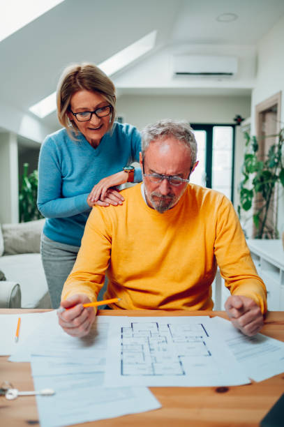 テーブルに座って新しい家の青写真を見ている老夫婦 - husband wife couple senior adult ストックフォトと画像