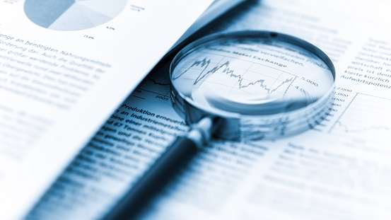 Magnifying glass, calculator and charts on paper symbolizing business and financial market. Blue toned image. studio shot in raw format taken with prime lens for best quality