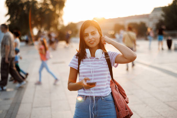 istock Young woman using maps app on her mobile phone while exploring city at sunset 1445708980