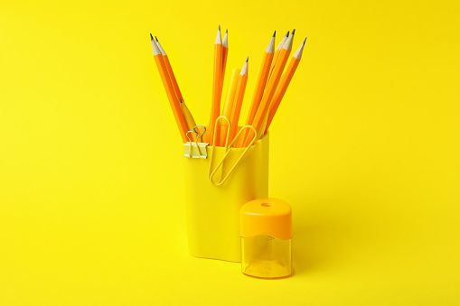 Holder with different stationery on yellow background