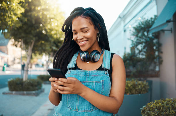 전화, 소셜 미디어 및 도시의 한 여성이 스트리밍, 오디오 또는 통신을 위해 모바일을 사용하는 여성과 함께합니다. 웹, 인터넷 및 젊은 여성이 문자 메시지를 읽거나 입력하는 네트워킹 - headphones people listening on 뉴스 사진 이미지