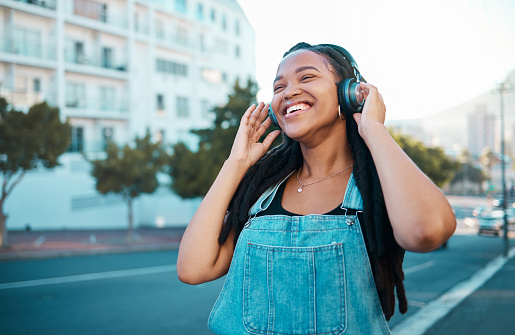 Music headphone streaming, happy and black woman smile outdoor from Atlanta. Happiness of a person feeling relax freedom and cheerful mindset listening to audio and song track near the street