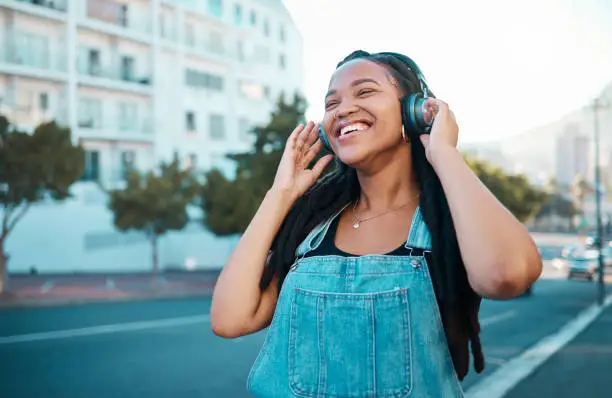 Photo of Music headphone city streaming, happy and black woman smile outdoor from Atlanta. Happiness of a person feeling relax freedom and cheerful mindset listening to audio and song track near the street