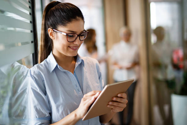 istock Attractive young businesswoman using a digital tablet while standing in front of windows in office 1445715317