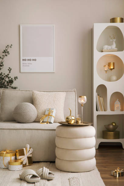 istock Amazing composition on white design shelf with mock up poster frame, christmas decoration, lights, gifts, lanterns ,deer, candles, stars, white corduroy sofa and pouf. Santa claus is coming. Home decor. Template. 1445715695