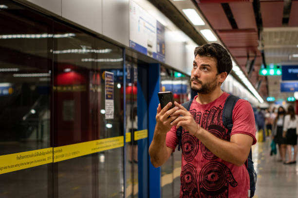 Young man waiting at the subway station. Handsome man in the subway station. Waiting for the subway. Tourist waiting for the subway. Tourist with cell phone in hand
