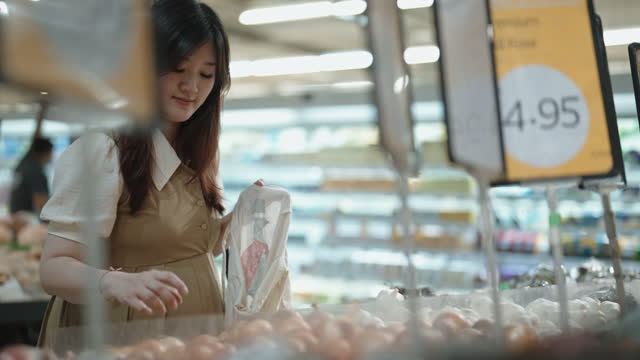 Asian Chinese pregnant woman buying onion in supermarket with reusable bag