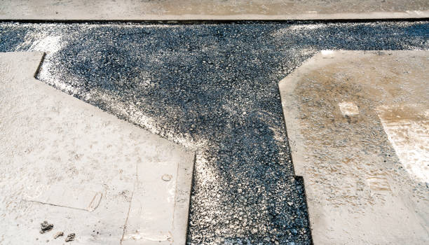Wet concrete surrounding newly laid asphalt following the installation of a pipeline below the street in Berlin, Germany.