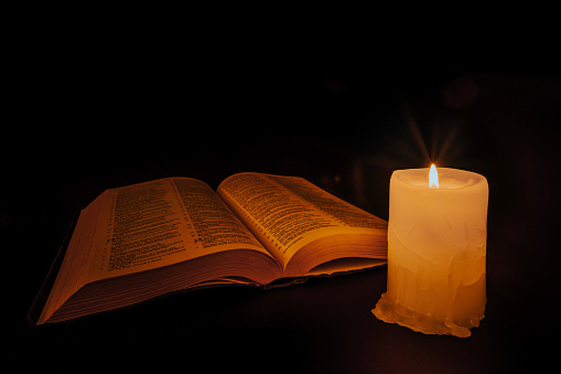bible on the table in the light of a candle