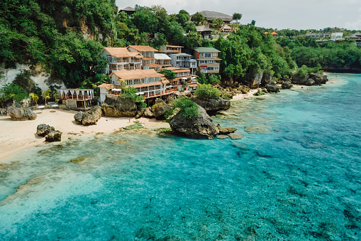 Aerial view of quiet blue ocean and coastline with cozy hotels on Impossibles beach in Bali island