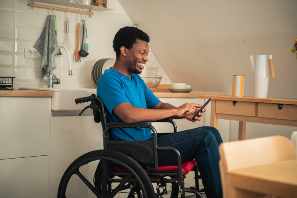 istock Young African American in a wheelchair using smartphone at home 1445720877