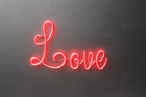 3d rendering of a neon sign with the word love in red on black rough wall