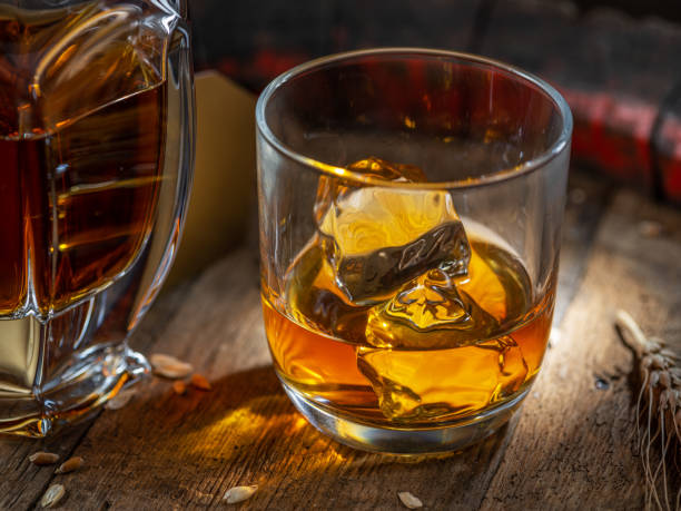 暗い背景にある古い木製の樽の上にウイスキーとウイスキーのガラスのキャラフェ。 - gin decanter whisky bottle ストックフォトと画像