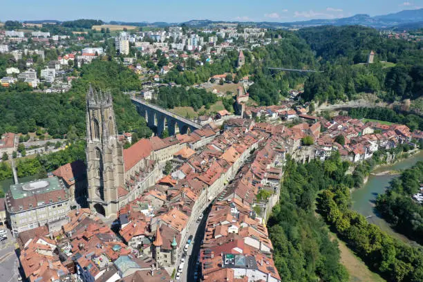 Fribour is a city at the cultural border between the German and French part of Switzerland (Romandy). The Image shows the historic old town of fribourg with the Fribourg Cathedral and the river Sarine during summer season.