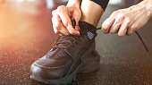 Close up of female hands tying shoelace on sports shoes before practice in the gym.