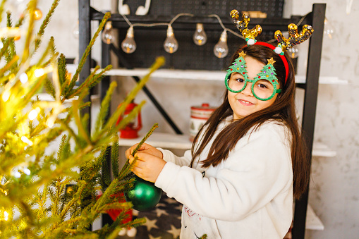 Smiling girl decorates Christmas tree