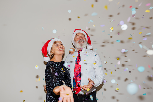 Portrait of a senior couple with Santa's hats celebrating New Year together.