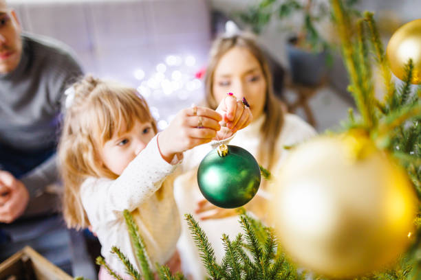 istock Little girl decorates Christmas tree while her parents watching 1445726891