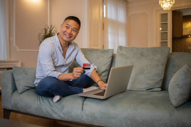 istock Cheerful man doing online shopping 1445732570