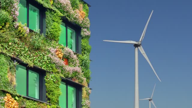 Green sustainable building in front of rotating wind turbines