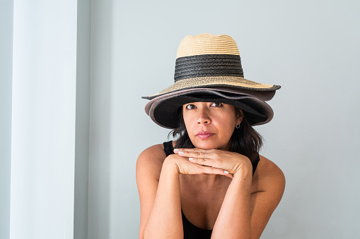 Woman wearing many different styles of hats, balancing on her head symbolizing collecting, fashion, shopping and different styles