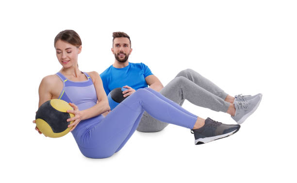 istock Athletic couple doing exercise with medicine balls on white background 1445738739