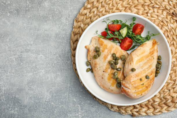 istock Delicious cooked chicken fillets with capers and salad on light grey table, top view. Space for text 1445740266