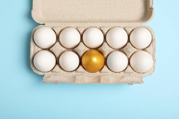 caja de cartón con huevos de gallina dorados y ordinarios sobre fondo azul claro, vista superior - carton multi colored easter egg easter fotografías e imágenes de stock