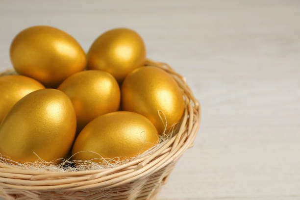 明るい背景に籐のバスケットに輝く金色の卵、接写。テキスト用のスペース - shiny group of objects gem bright ストックフォトと画像