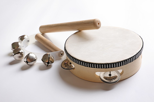 Wooden tambourine, rhythm stick and hand bells on white background. Montessori musical toy