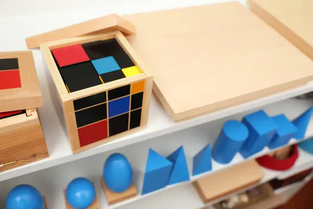 Set of wooden geometrical objects and other montessori toys on shelves