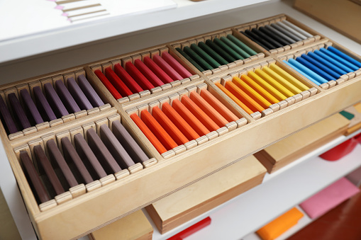 Wooden box with color tablets and other montessori toys on shelves