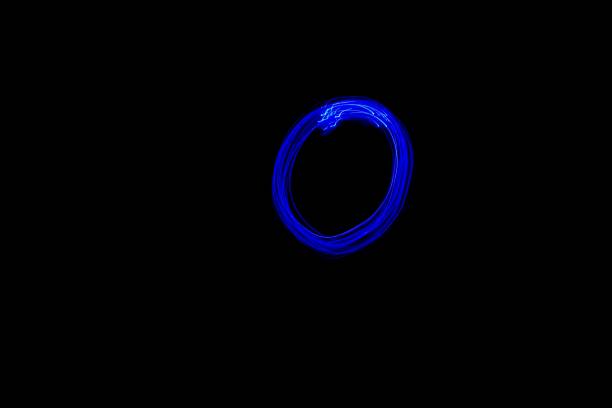 Light painting blue letter O on black background. Long exposure photo.