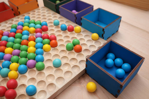 tábua de triagem de madeira e caixas com bolas coloridas sobre a mesa, close-up. brinquedo montessori - perceção sensorial - fotografias e filmes do acervo