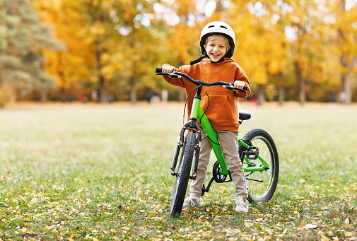 happy cheerful child boy riding a bike in autumn Park in nature