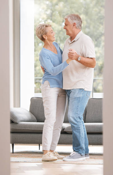 un couple de personnes âgées danse ensemble pour la retraite, l’immobilier ou la célébration du mariage avec bonheur dans une nouvelle maison. les personnes âgées dansent sur de la musique avec amour, soins et bien-être dans le salon - senior couple senior adult pension couple photos et images de collection