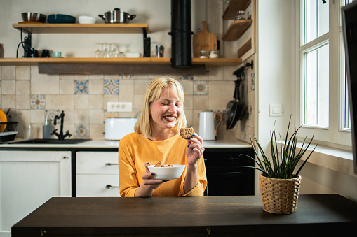 Portrait of a beautiful young woman snacking cookies at home