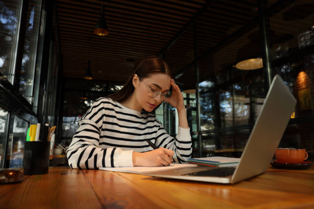 istock Young female student with laptop studying at table in cafe 1445752929