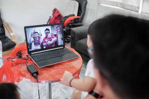 Asian Chinese family with children video conferences thru laptop during Chinese new year