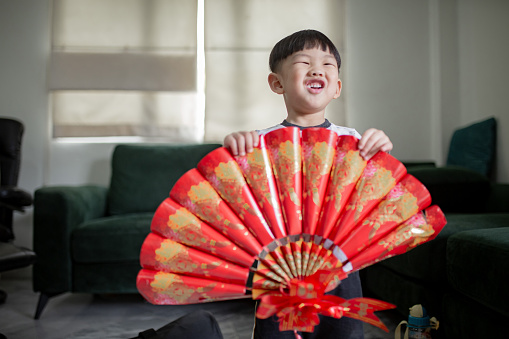 Asian Chinese boy holding DIY Craft fan with smiling face during Chinese New Year