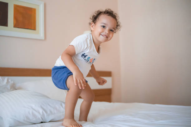 istock Curly toddler boy jumping and having fun on the bed 1445756627