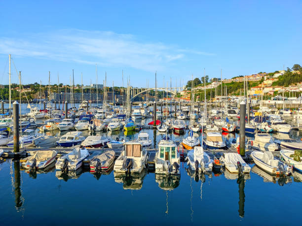 Marina with moored sailboats and yachts, reflection on water, sunhine evening, Arrabida bridge, Porto, Portugal