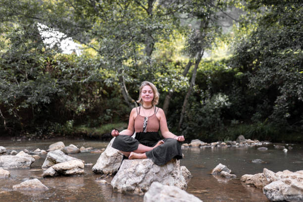 istock A young blonde woman is meditating sitting on a river rock 1445757183