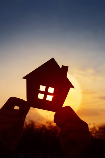 Hands holding paper house on sunset sky, family home, homeless housing, and home protection insurance concept, international day of families, new life, foster home care, and real estate. manos sosteniendo casa de papel en el cielo del atardecer, hogar familiar, vivienda para personas sin hogar y concepto de seguro de protección del hogar, día internacional de las familias, nueva vida, cuidado en hogares de acogida y bienes raíces.