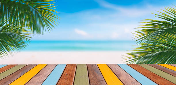 istock multicolored top table and palm tree and tropical beach background. 1445758593
