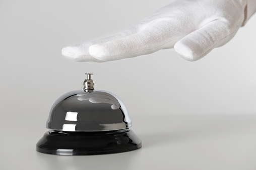 Hand with white glove is touching a service bell.