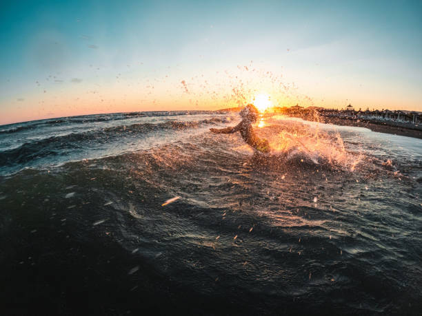 istock Boy Splashing In Sea Waves At Sunset 1445759115