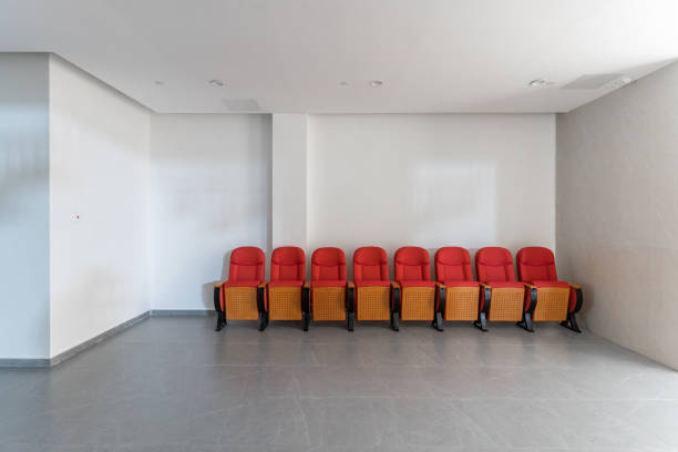 A row of idle red sofa chairs beside the white wall