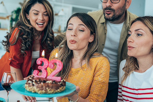 Young woman celebrating her 32nd birthday with friends at home